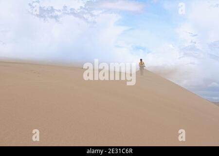 Tourist walking along the edge of the sand dune. Large barkhan in Mongolia sandy dune desert Mongol Els. Govi-Altay, Mongolia.