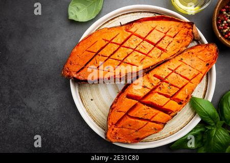 Two halves of baked yam sweet potato with spices and herbs, top view Stock Photo