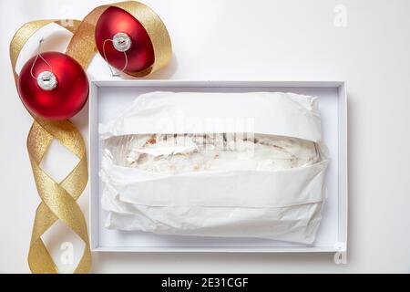 Christmas stollen cake Christstollen isolated on white. Sweet german traditional bread wraped with paper  in a carton box and seasonal decoration. Xma Stock Photo