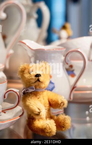 Vintage 1950s Steiff miniature stuffed animal bear and a child's tea set. Stock Photo