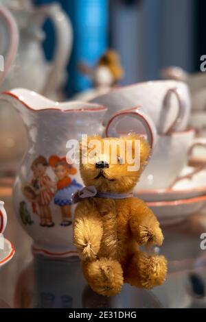 Vintage 1950s Steiff miniature stuffed animal bear and a child's tea set. Stock Photo