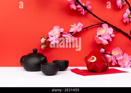 Year of Ox Piggy Bank, Sakura Cherry Blossom, Black Chinese Teapot and Red Envelope Angpow on White and Red Chinese New Year Backgrounds Stock Photo
