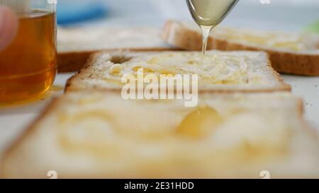 Morning Breakfast with a Person Spreading Sweet Honey on a Toast Stock Photo