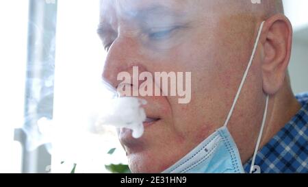 Image with a Man who Smokes a Cigarette Using on the Face a Protective Mask Against Virus Infection Stock Photo
