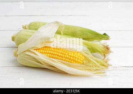 Three ripe ears of corn on white wooden table Stock Photo