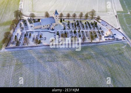 Jutland, Denmark -  A typical old fashioned church surrounded by country farm fields and winter trees. Stock Photo