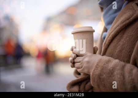 Woman holding a takeaway coffee on the Christmas market background Stock Photo