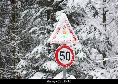 snow covered traffic signs in winter, speed limit 50 and attention traffic light Stock Photo