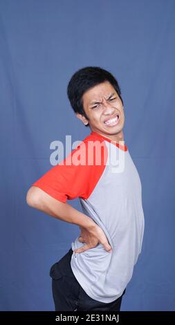 Asian man back pain isolated blue background Stock Photo