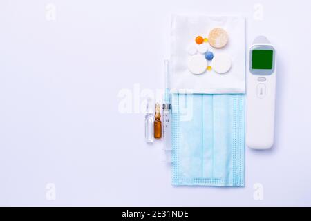 Medical equipment on a white background. Non-contact thermometer, medicines, syringe and ampoules. View from above. Stock Photo