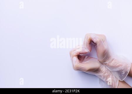 Doctor's hands in medical gloves in shape of heart on blue