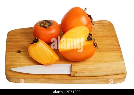 Persimmons on wooden kitchen cutting board isolated on white Stock Photo