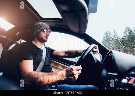 A man wearing glasses and a black T-shirt drives a car with concentration - street racing Stock Photo