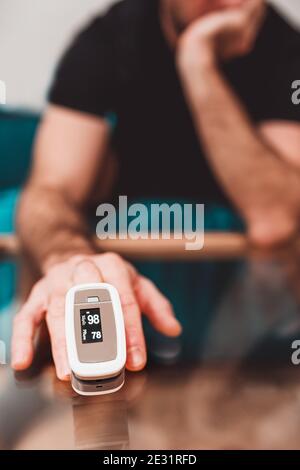 Self-diagnosis at home - Caucasian male finger pulse oximeter - self-monitoring of blood saturation Stock Photo