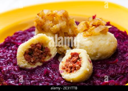 potato dumplings filled with smoked meat with fried onion on red cabbage Stock Photo