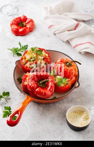 Red bell peppers stuffed with rice and vegetables on cast iron pan on gray concret background. Stock Photo