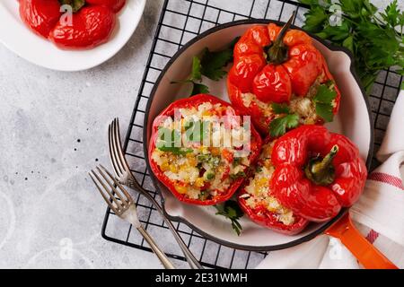 Red bell peppers stuffed with rice and vegetables on cast iron pan on gray concret background. Stock Photo