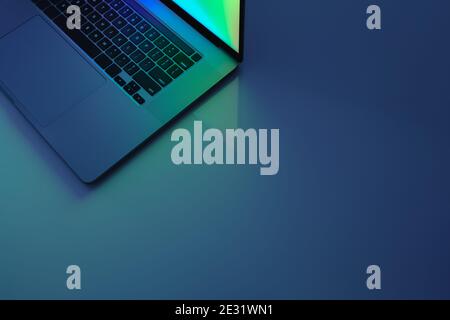 Laptop computer standing on a table, low key blue light image. Concept of working at home, blue light, minimalistic work desk Stock Photo