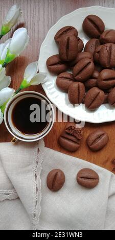 Chocolate cookies in the form of coffee beans next to a cup of coffee Stock Photo