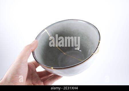 Gray Kintsugi bowl, real gold restoration, japanese technique Stock Photo