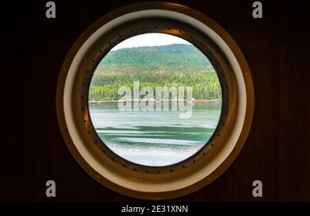 Porthole window view along the Inside Passage cruise, Vancouver island, British Columbia, Canada. Focus on landscape. Stock Photo