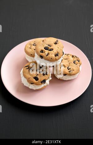 Homemade Chocolate Chip Cookie Ice Cream Sandwich on a pink plate on a black background, low angle view. Stock Photo