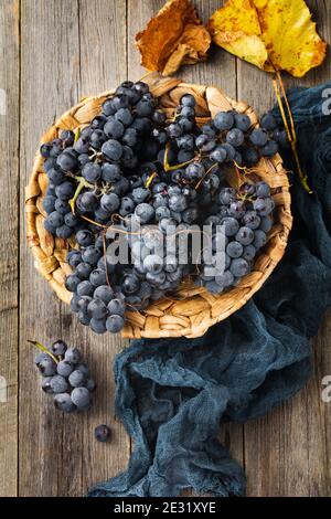 Vintage textured rattan plate and grape wine on old wooden background. Vintage Style. Top view. Stock Photo