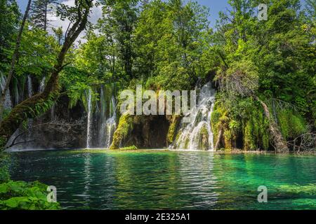 Closeup on waterfalls, covered in lichens illuminated by sunlight. Green lush forest in Plitvice Lakes National Park UNESCO World Heritage, Croatia Stock Photo