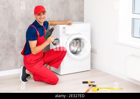 male adult repairman with tool and clipboard checking washing machine in bathroom Stock Photo