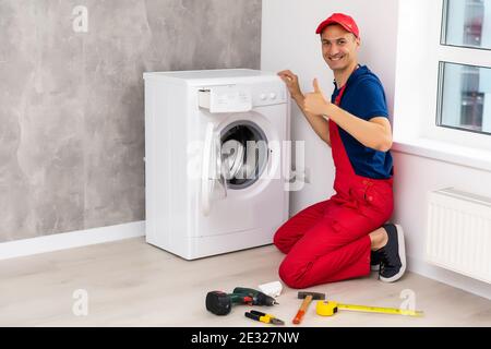 male adult repairman with tool and clipboard checking washing machine in bathroom Stock Photo