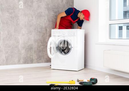 male adult repairman with tool and clipboard checking washing machine in bathroom Stock Photo