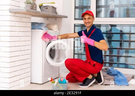 male adult repairman with tool and clipboard checking washing machine in bathroom Stock Photo