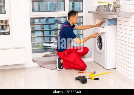 male adult repairman with tool and clipboard checking washing machine in bathroom Stock Photo