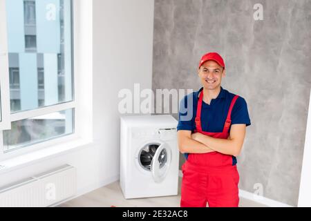 male adult repairman with tool and clipboard checking washing machine in bathroom Stock Photo