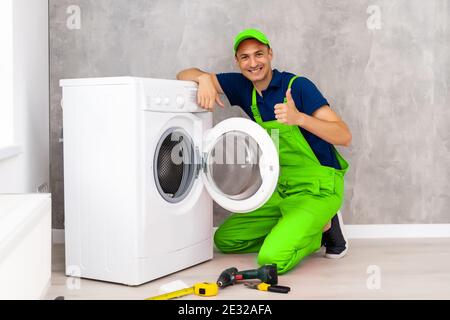 male adult repairman with tool and clipboard checking washing machine in bathroom Stock Photo