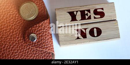 yes and no words on wooden blocks, brown leather wallet coins and luxury pen. Business decision making concept. Stock Photo