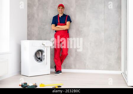male adult repairman with tool and clipboard checking washing machine in bathroom Stock Photo