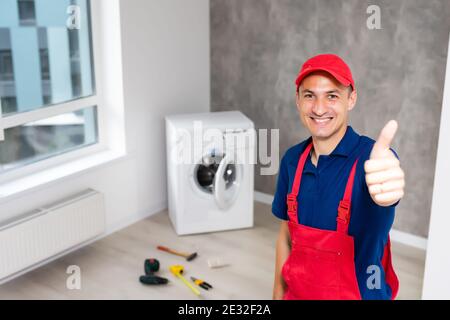 male adult repairman with tool and clipboard checking washing machine in bathroom Stock Photo