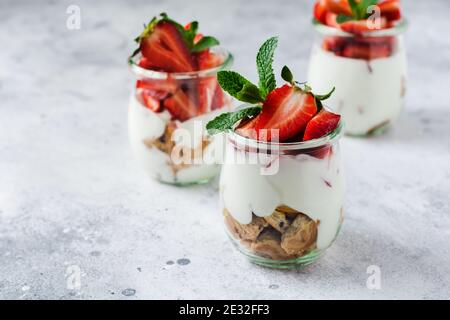 No baked dessert treifl or cheesecake with strawberries in sliced jars on an old concrete background. Selective focus. Stock Photo