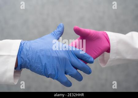 During the development of the COVID19 vaccine, the two laboratories reconciled, and as a sign of this consent, he took his hands together in a gesture of further cooperation. Gray blurry background. Close-up view. Stock Photo