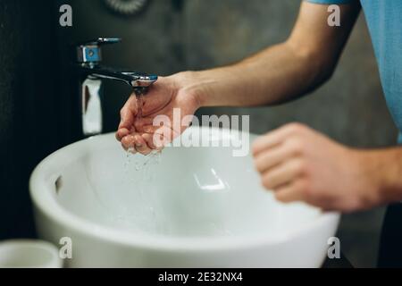 close-up photo young man washing hand in bathroom early in the morning. Stock Photo