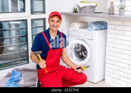male adult repairman with tool and clipboard checking washing machine in bathroom Stock Photo