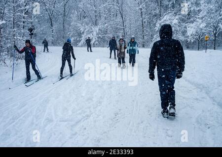 Montreal, CA - 01 January 2021: People walking and skiing on a snowy trail in Montreal's Mount Royal Park (Parc Du Mont-Royal) during snowstorm. Stock Photo