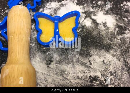 Cookie cutter mold in shape of a blue butterfly on the black board, rolling pin Stock Photo