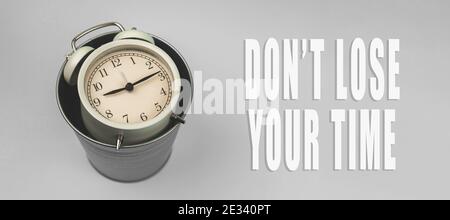 Inspirational and motivational quotes concept, don't lose your time background banner, alarm clock and trash bin Stock Photo