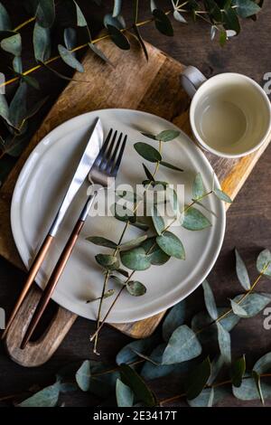 Place setting with fresh eucalyptus leaves on wooden table Stock Photo
