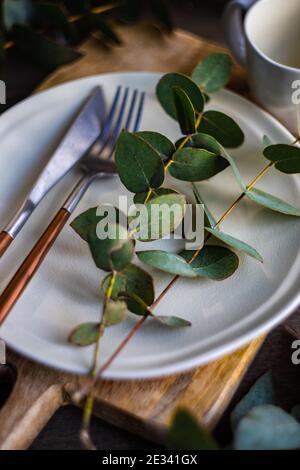 Place setting with fresh eucalyptus leaves on wooden table Stock Photo