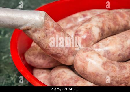 Cooking sausages from raw minced meat using a natural shell and meat grinder at home close up. Stock Photo
