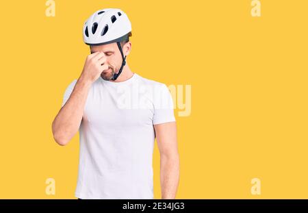 Young handsome man wearing bike helmet tired rubbing nose and eyes feeling fatigue and headache. stress and frustration concept. Stock Photo