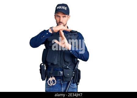 Young handsome man wearing police uniform doing time out gesture with hands, frustrated and serious face Stock Photo